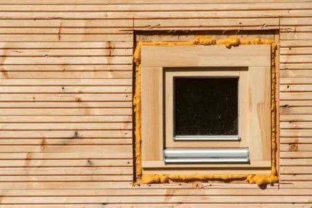 Wooden window. Foam window insulation on wooden construction. Building an eco-house. Heat insulation
