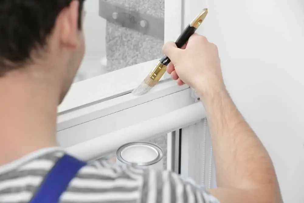 Young worker painting window in office