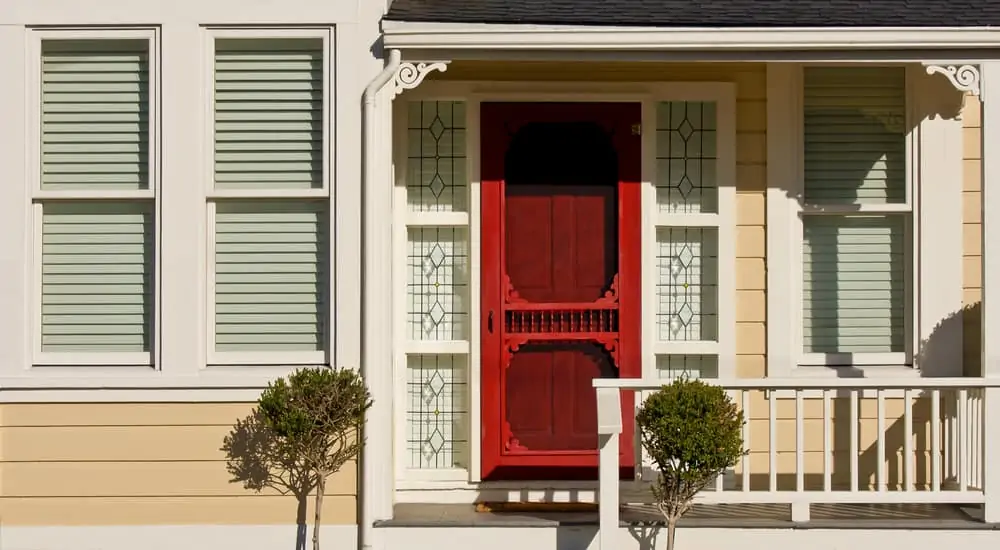 A detail of a simple Victorian-style home, including porch and sash windows.