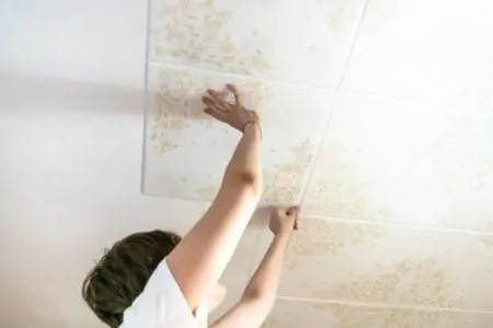girl fixes styrofoam ceiling tiles at home