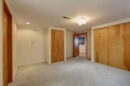 Empty basement room with closets. Wooden sliding doors