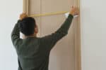 Man measure the door size and write on paper at home