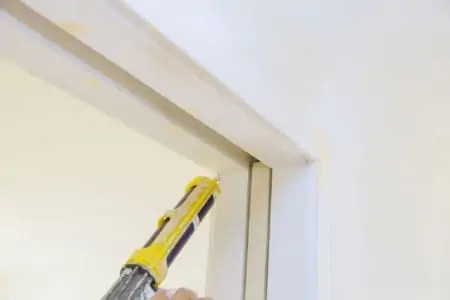 Applying silicone on molding door trim with caulking gun tool