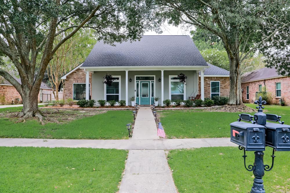 A front view of an Acadian renovated home with columns, sidewalks and a colorful front door recently purchased with the changing real estate market.