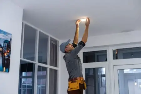 An electrician is installing spotlights on the ceiling