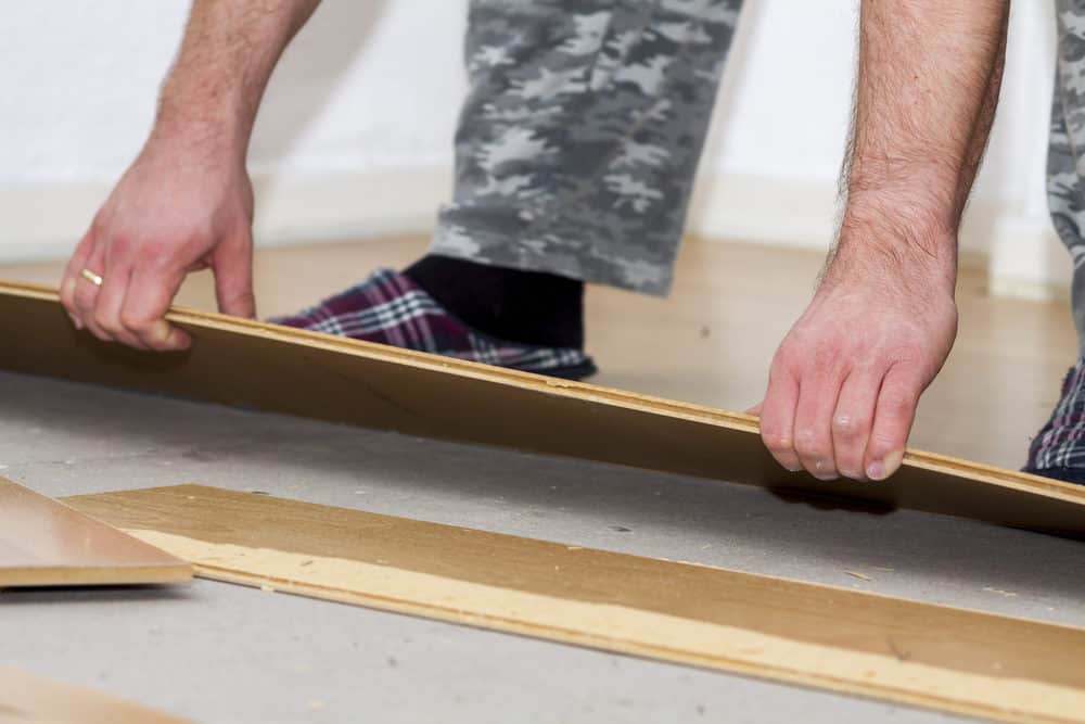 Man removing laminate of floor in house shoes