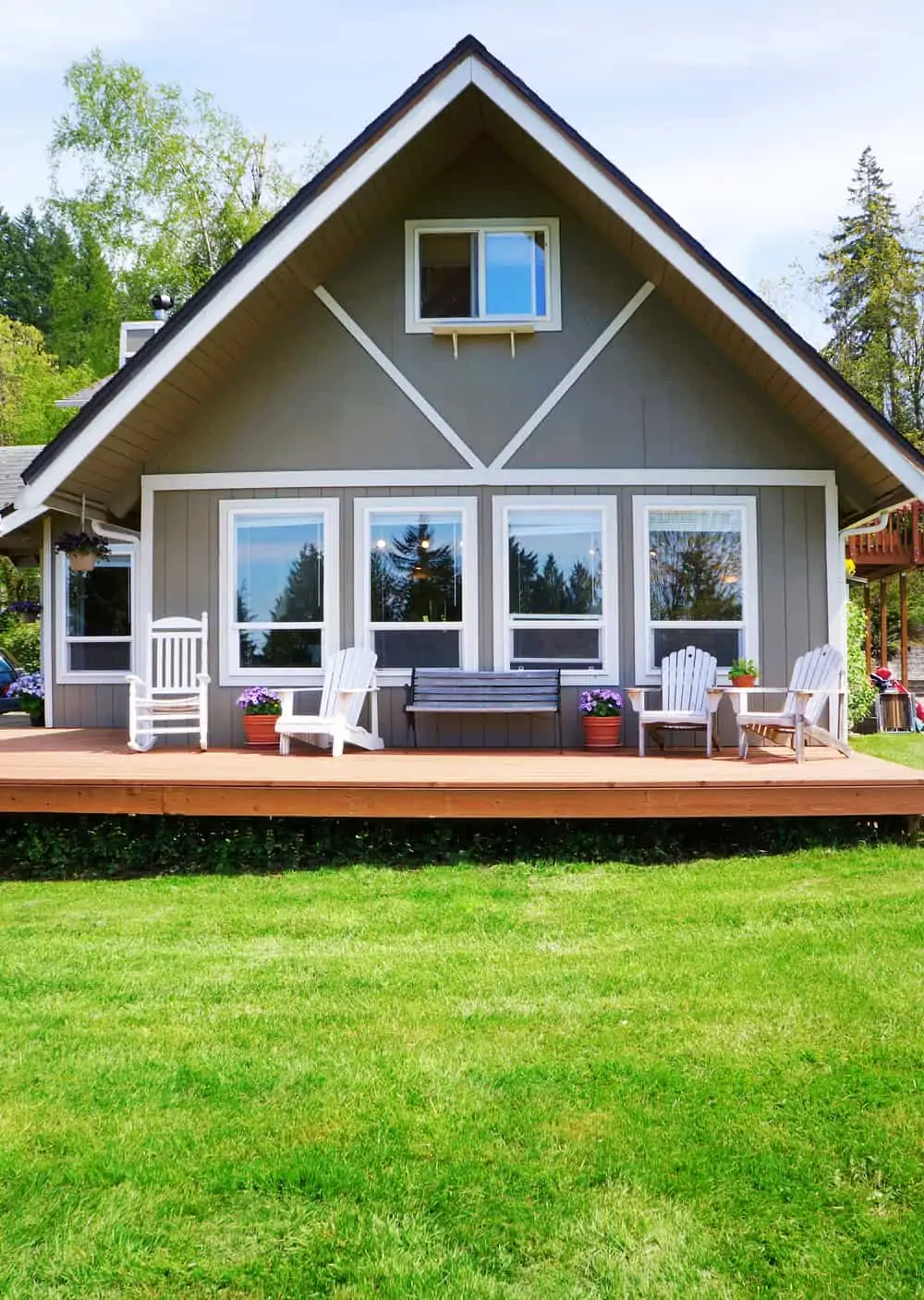 Modern American farm cottage hosue exterior with deck and wite chairs.