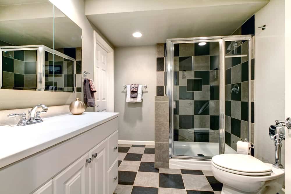 White bathroom with black and beige tile floor and glass shower