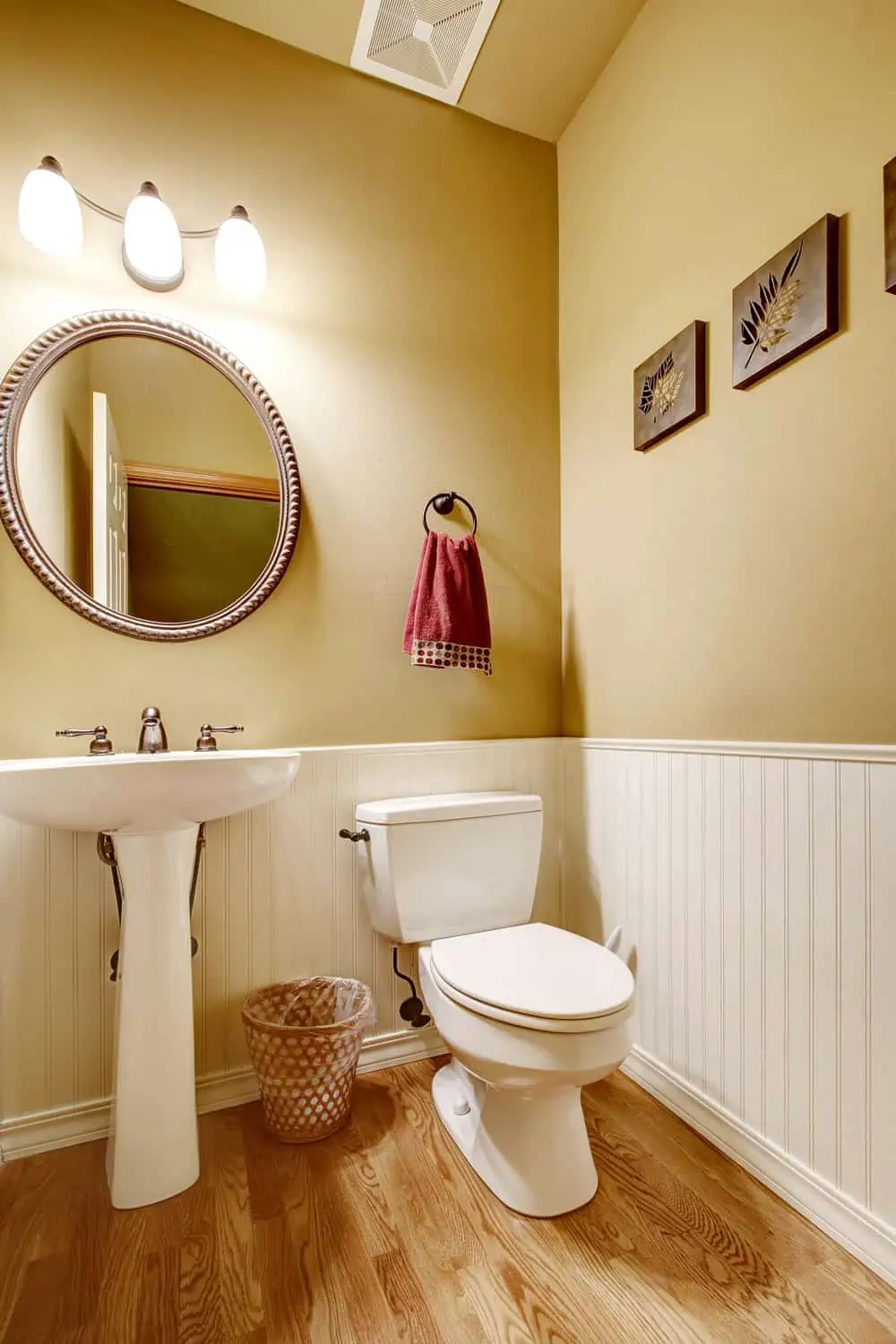Small bathroom with white washbasin stand and toilet. Beige wall with white trim