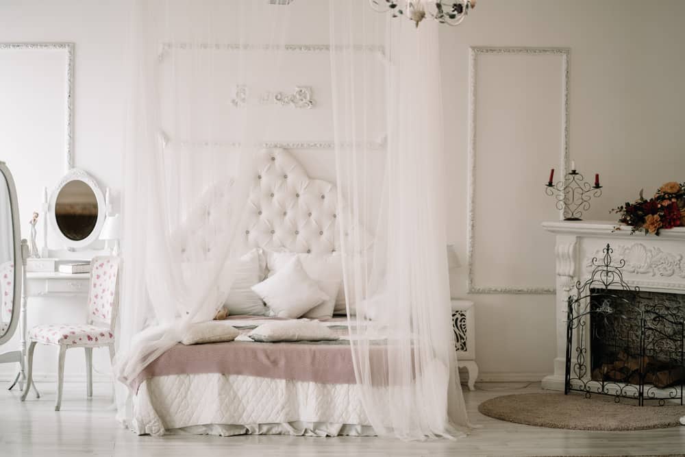 White bedroom interior with nobody. large cozy bed with a white canopy and oval dressing mirror with dressing table