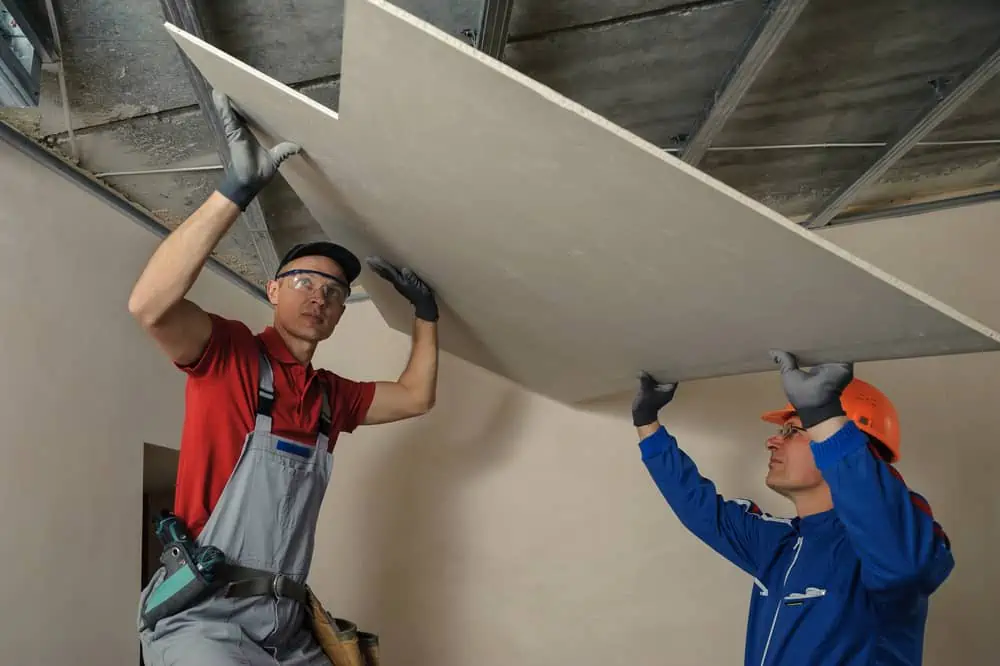 Drywall Installers. Men holding a gypsum board figured cut