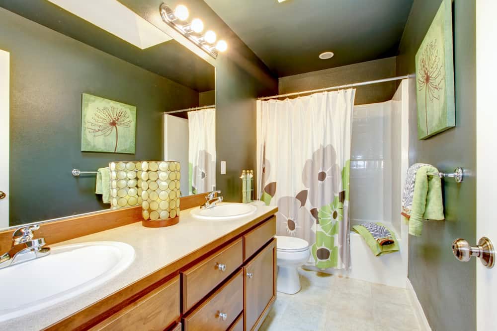 Green bathroom with wood cabinet and shower tub.