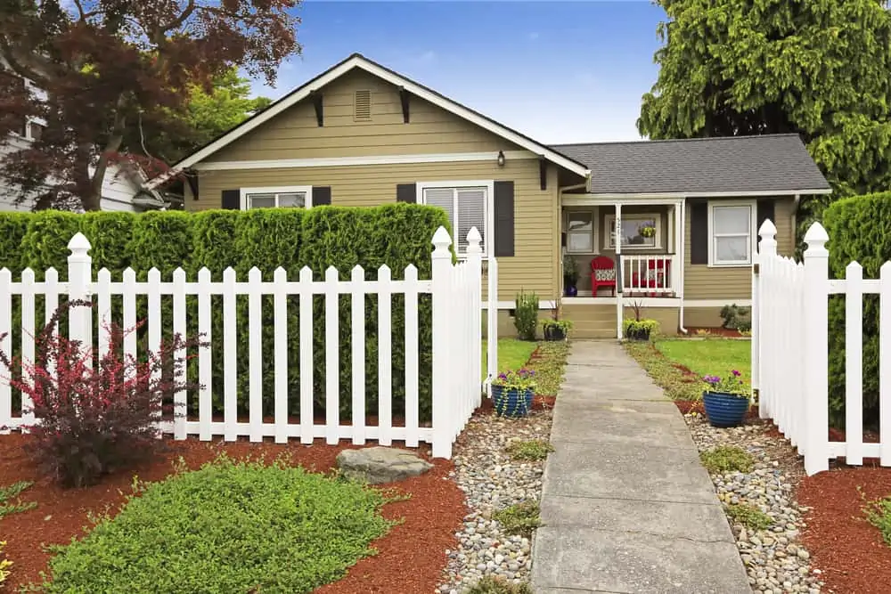 American house exterior with curb appeal. White wooden fence with concrete walkway