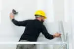 worker plastering gypsum board wall.