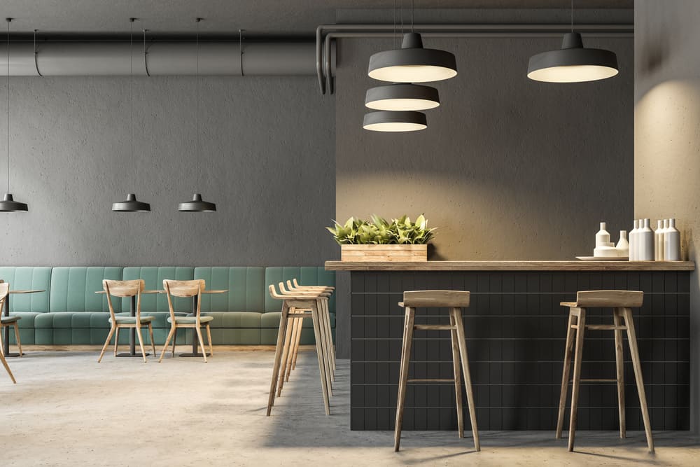 Industrial style bar interior with dark gray walls, a concrete floor, arched windows and wooden tables with chairs. Green sofas. 3d rendering mock up