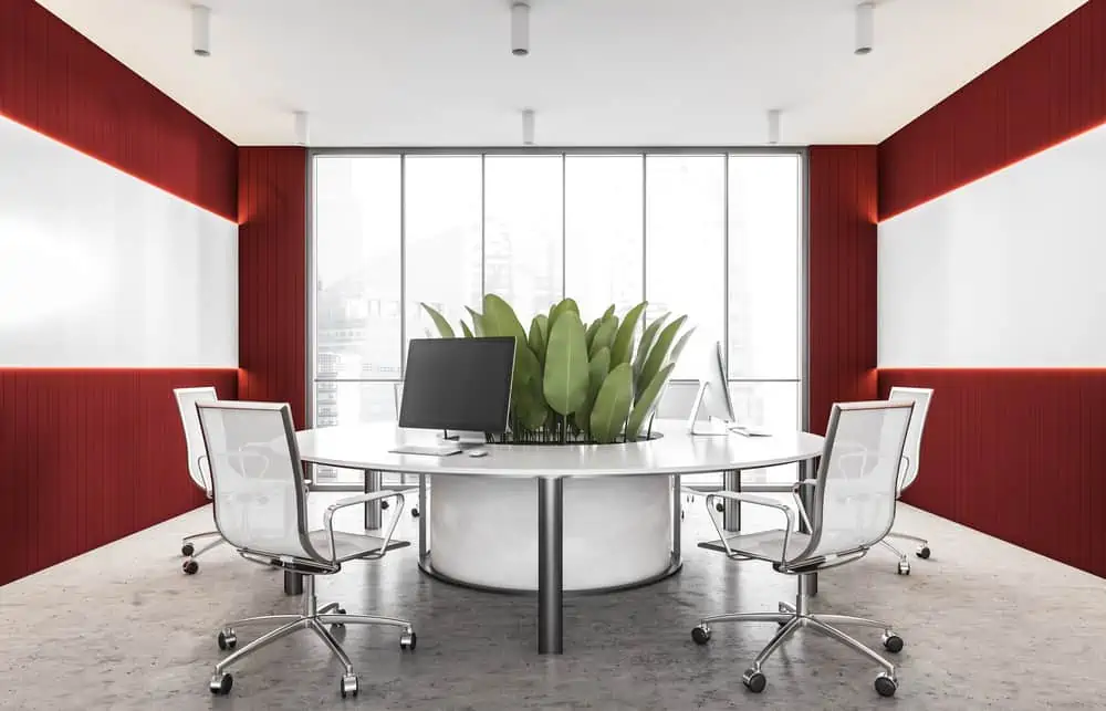 Interior of modern open space office with white and red walls, concrete floor and round computer table. 3d rendering