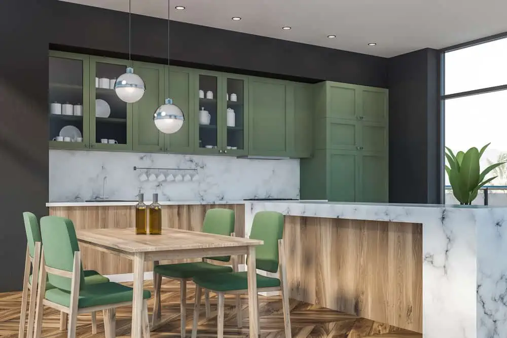 Corner of luxury kitchen with gray and marble walls, wooden floor, large window, wooden countertops, green cupboards, marble island and dining table with green chairs. 3d rendering