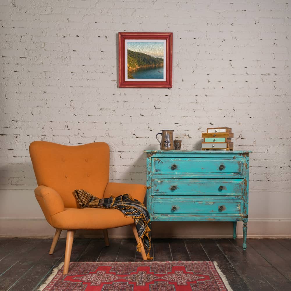 Vintage turquoise cabinet with orange stylish armchair in room interior