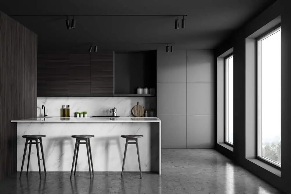 Interior of minimalistic kitchen with grey and marble walls, concrete floor, loft windows, white marble bar with stools and dark wooden countertops. 3d rendering