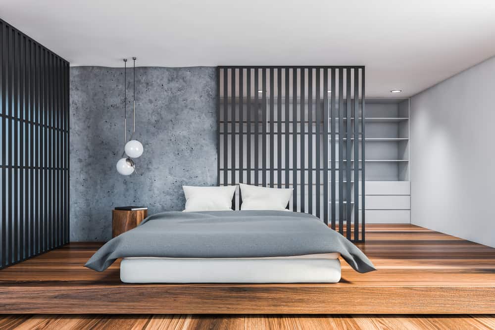 Front view of stylish loft bedroom with gray and white walls, dark wooden floor, comfortable king size bed, round bedside table and shelves in background. 3d rendering