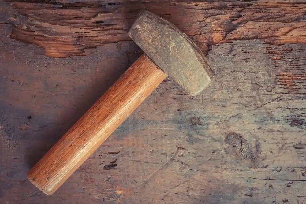 Small single handed worn sledge hammer on grunge wood background