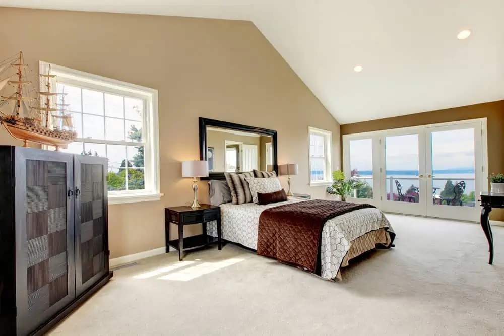 Beige classic large bedroom with water view and carpet.