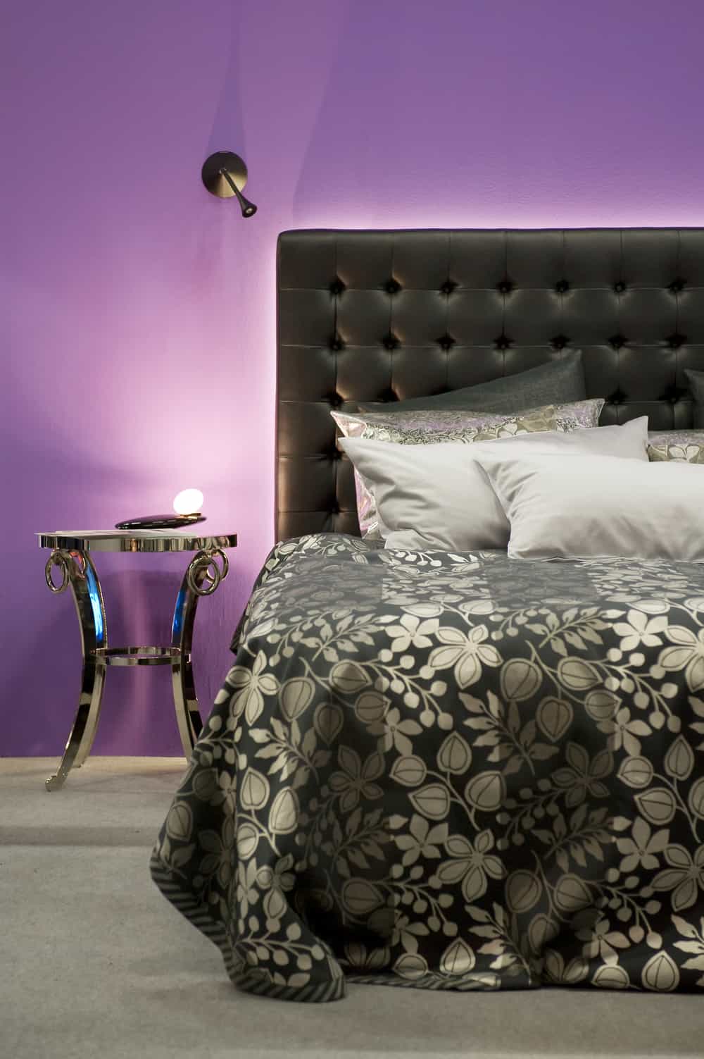 Bett vor einer lilafarbenen Wand Bed in front of a purple wall