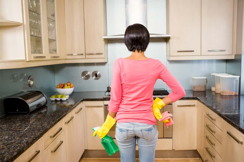 Rear view of standing brunette ready to clean the kitchen with yellow gloves