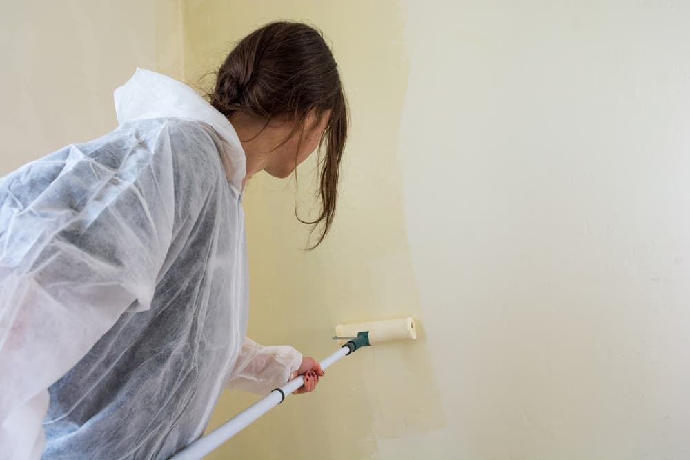 Young female student painting her room. Millenial redecorating.