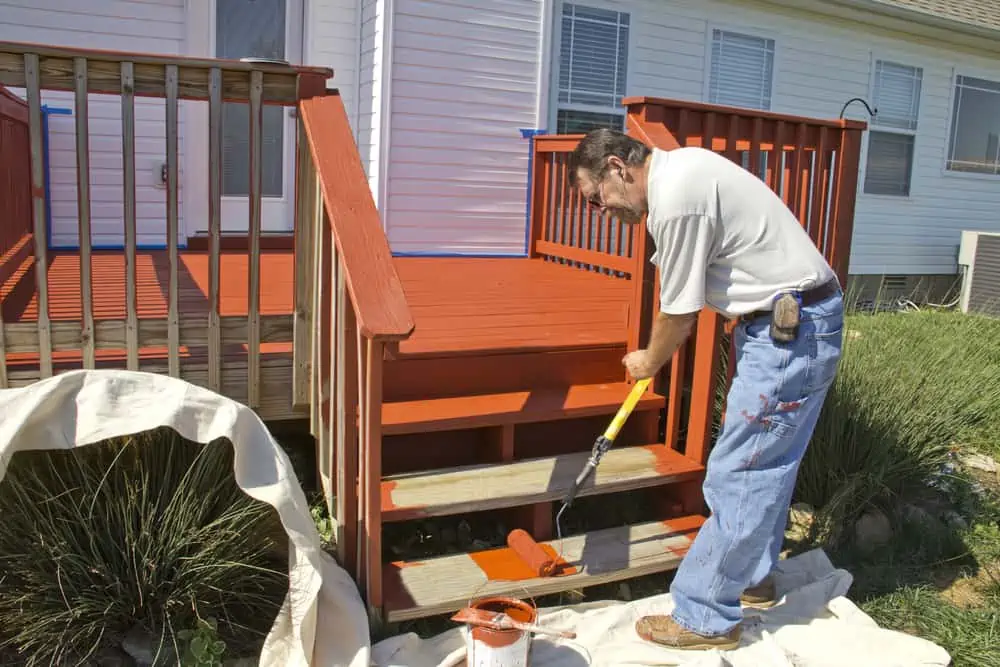 Contract painter staining deck on home