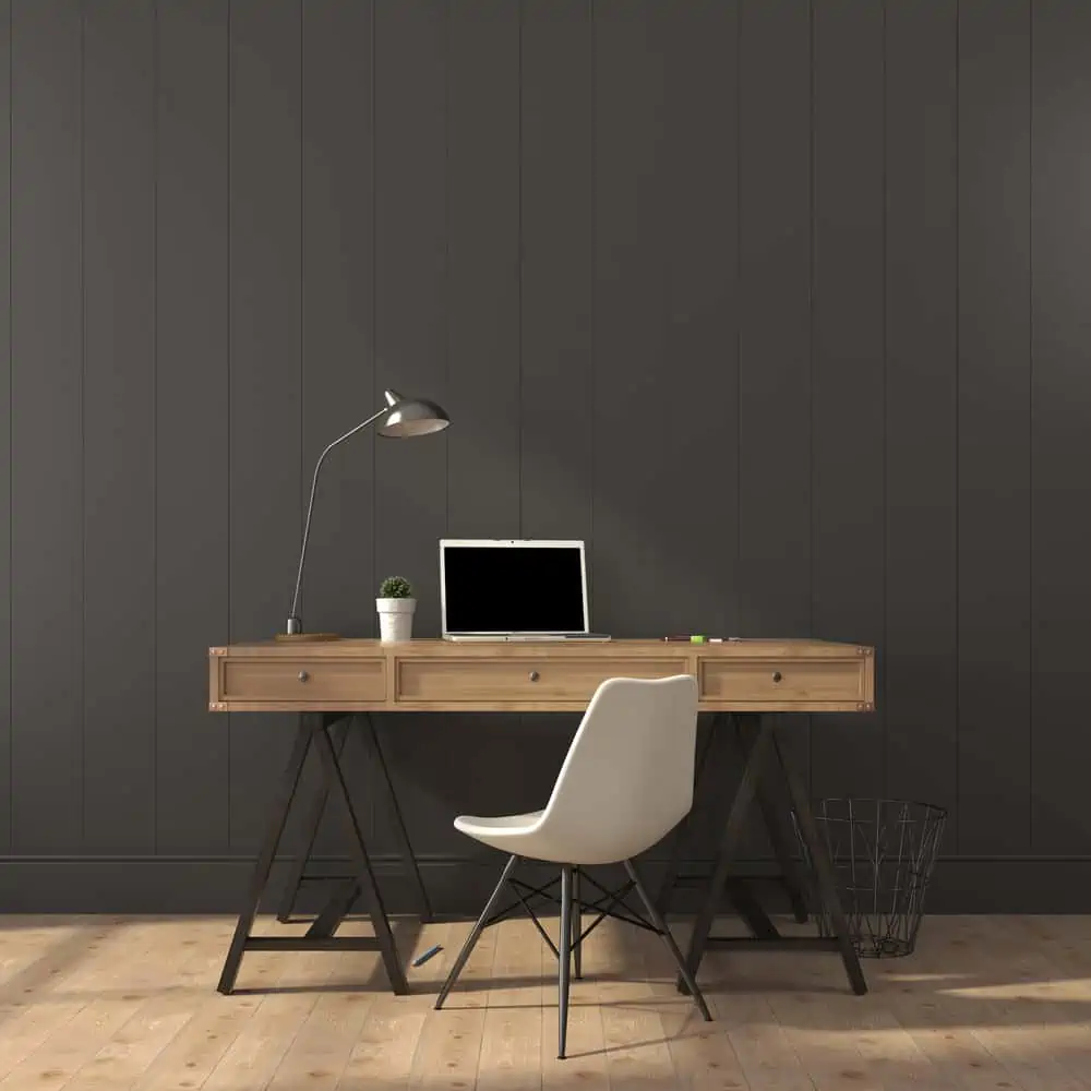 Wooden desk and modern chair against a gray wall