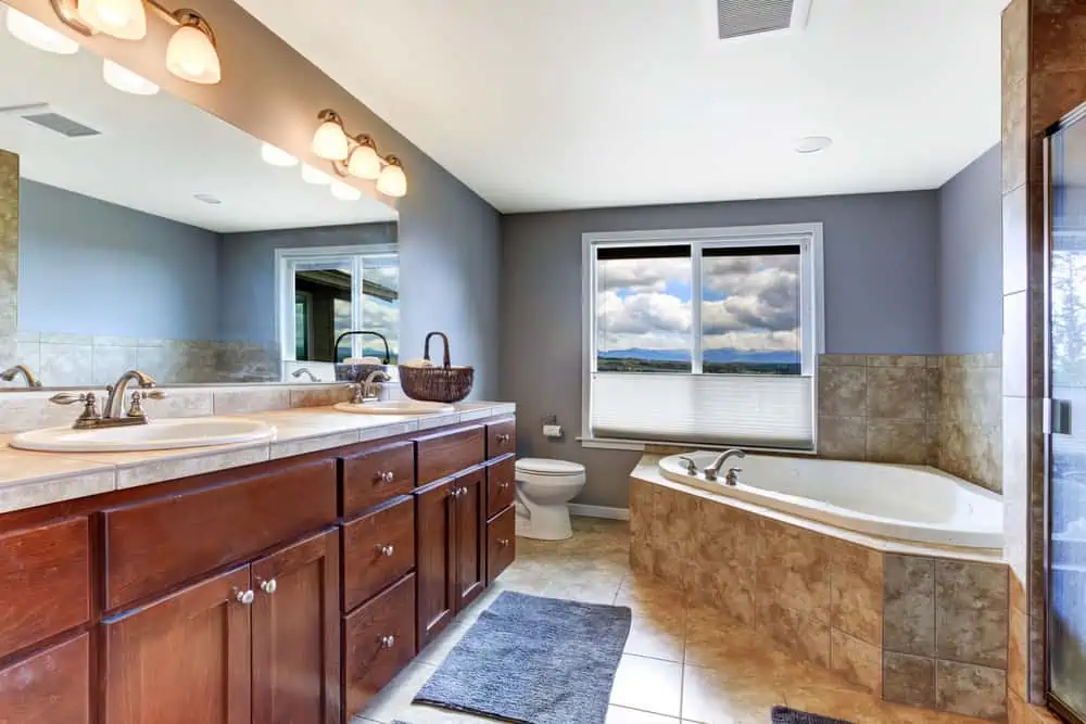 Lavender bathroom with brown bathroom vanity cabinet and mocha tile bath tub trim