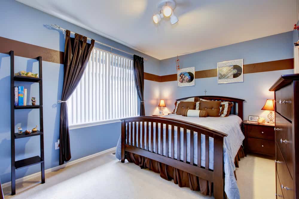 Guest bedroom with periwinkle blue color interior and brown wood bed frame.