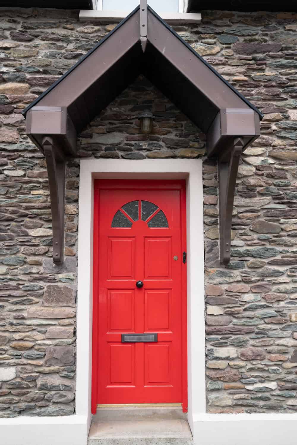 Red door under gable shelter in stone wall