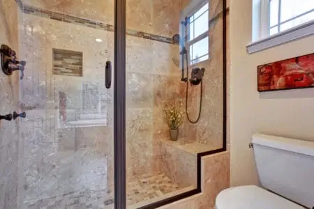 View of glass door shower with tile wall and floor.