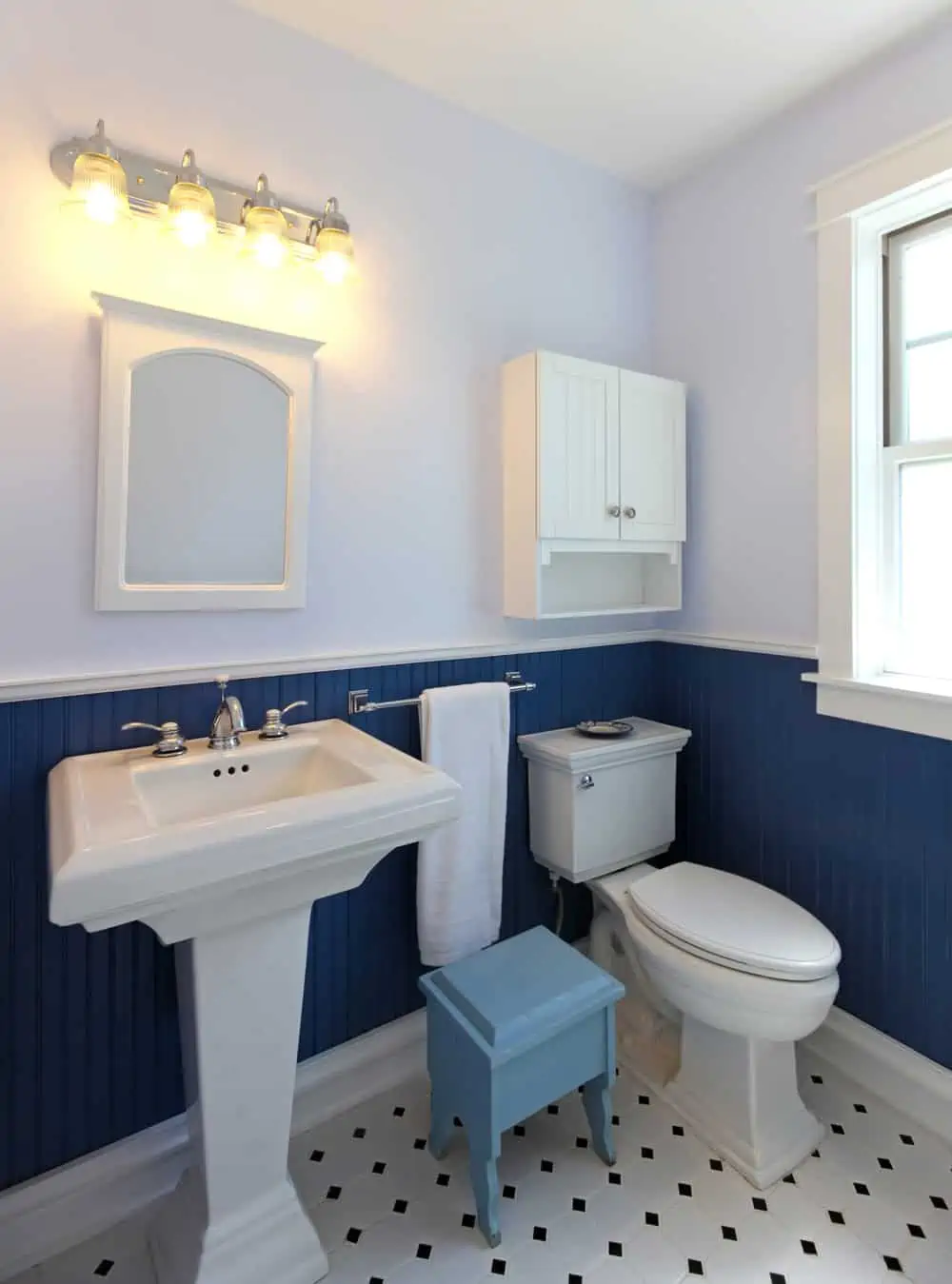 Bathroom with sink and toilet with blue walls and tile floor.