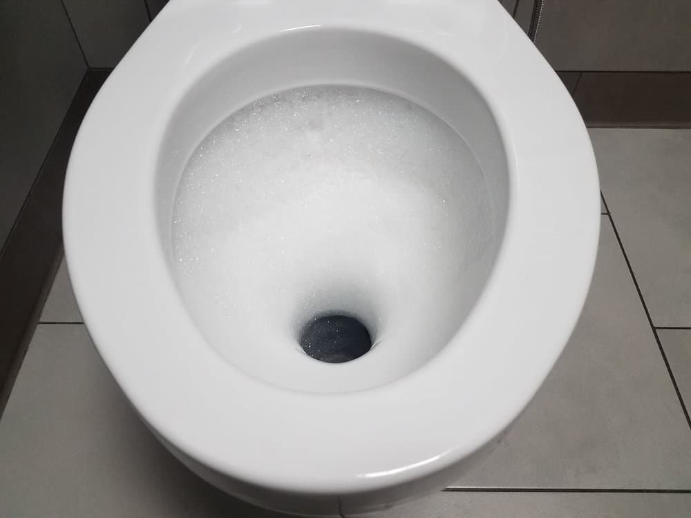white toilet with bubbles in restroom or bathroom
