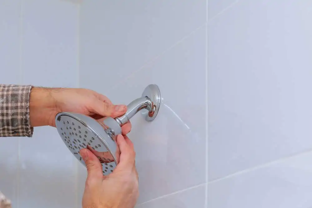 Workman repairing shower head the plumbing in the bathroom mounted shower holder with height adjustable a shower head.