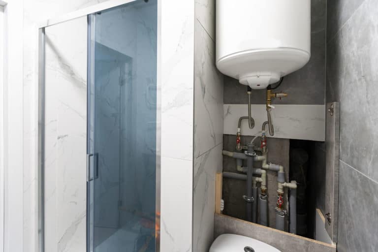 Water pipes, valves and manometers inside house, system with electric pumps and heaters. Metal pipeline of home boiler, cold and hot tubes on utility room wall. Modern pipe installation for heating