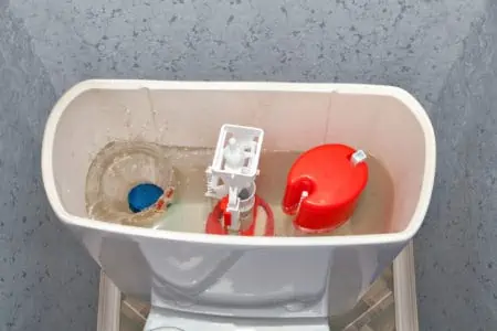 Blue cleaning water-soluble tablet falls into the water drain the toilet tank.