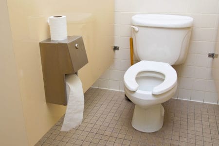 A roll of toilet paper next to a toilet in a bathroom