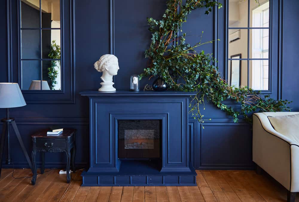 Modern interior with fireplace, spacious living room with blue walls and wooden floors. A real photo of the interior.