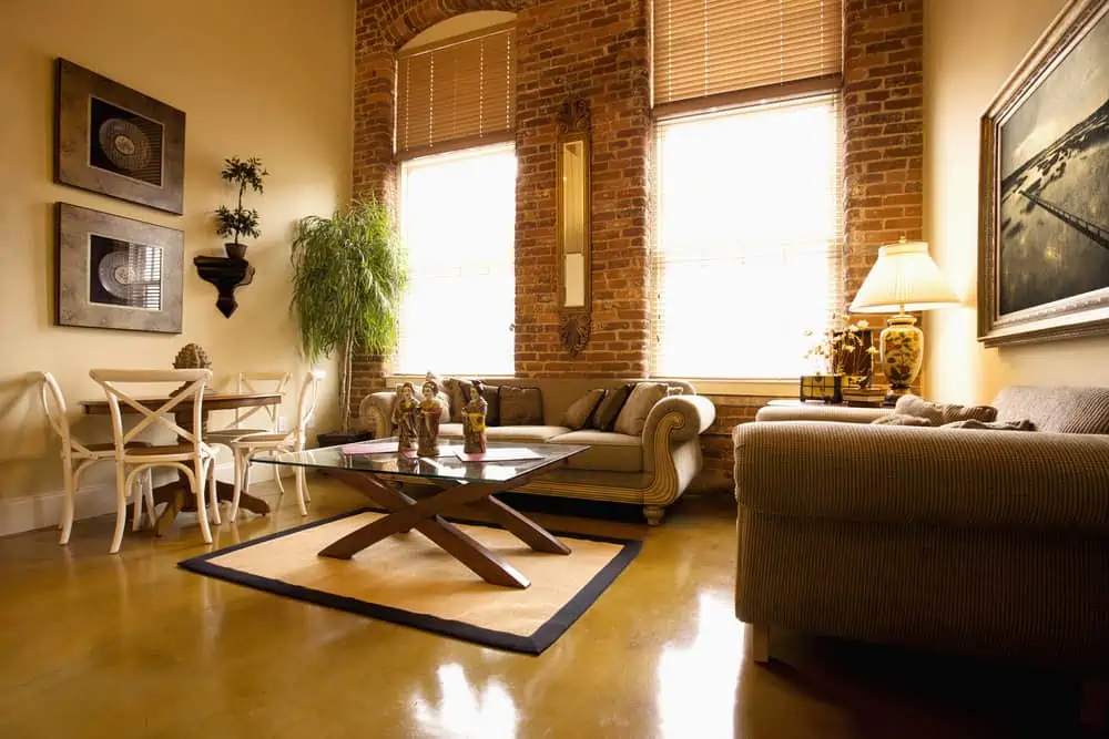 Interior of furnished living room with large windows and brick wall. Horizontal shot.