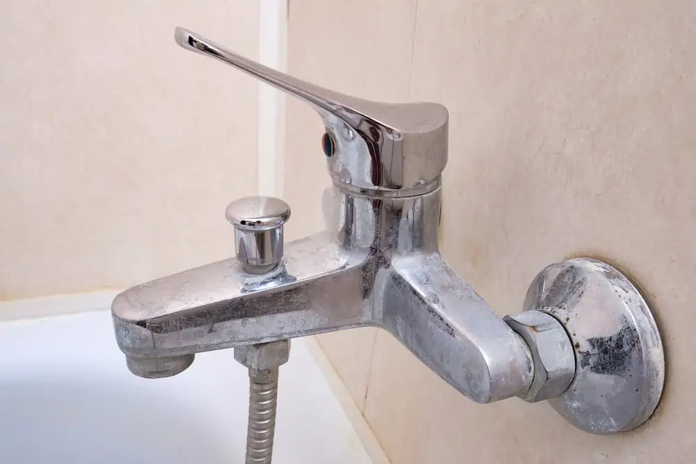 Dirty calcified shower mixer tap, faucet with limescale on it, close up