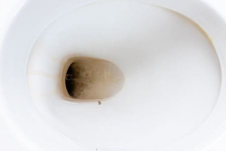 Dirty unhygienic toilet bowl with limescale stain at public restroom close up.