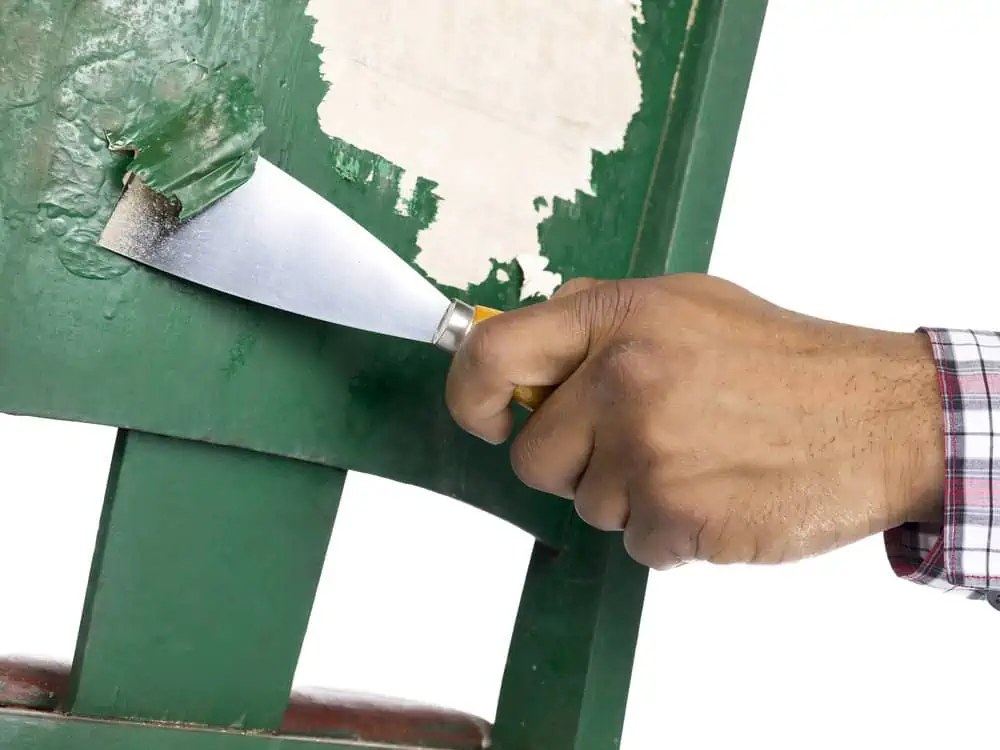 hand removing paint using trowel