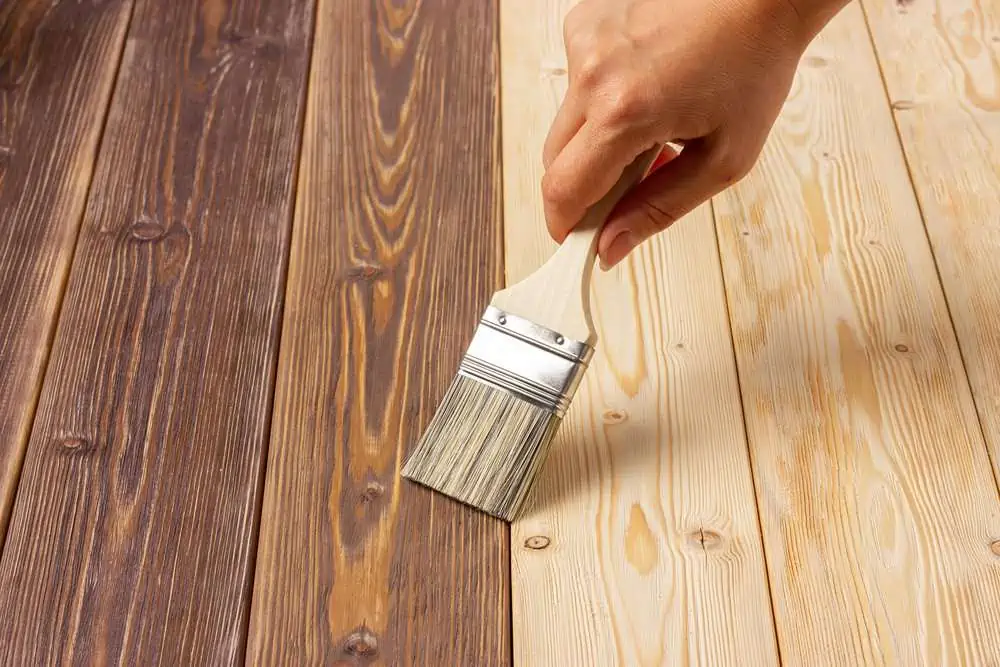 Hand holding brush on brown and light board wood