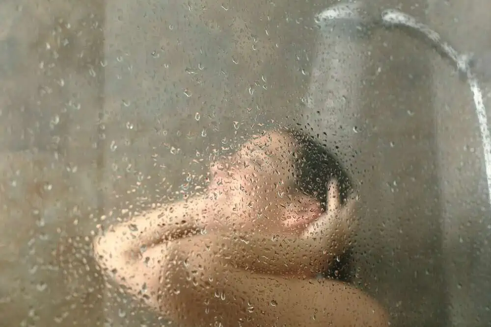 Woman showering through the bath screen