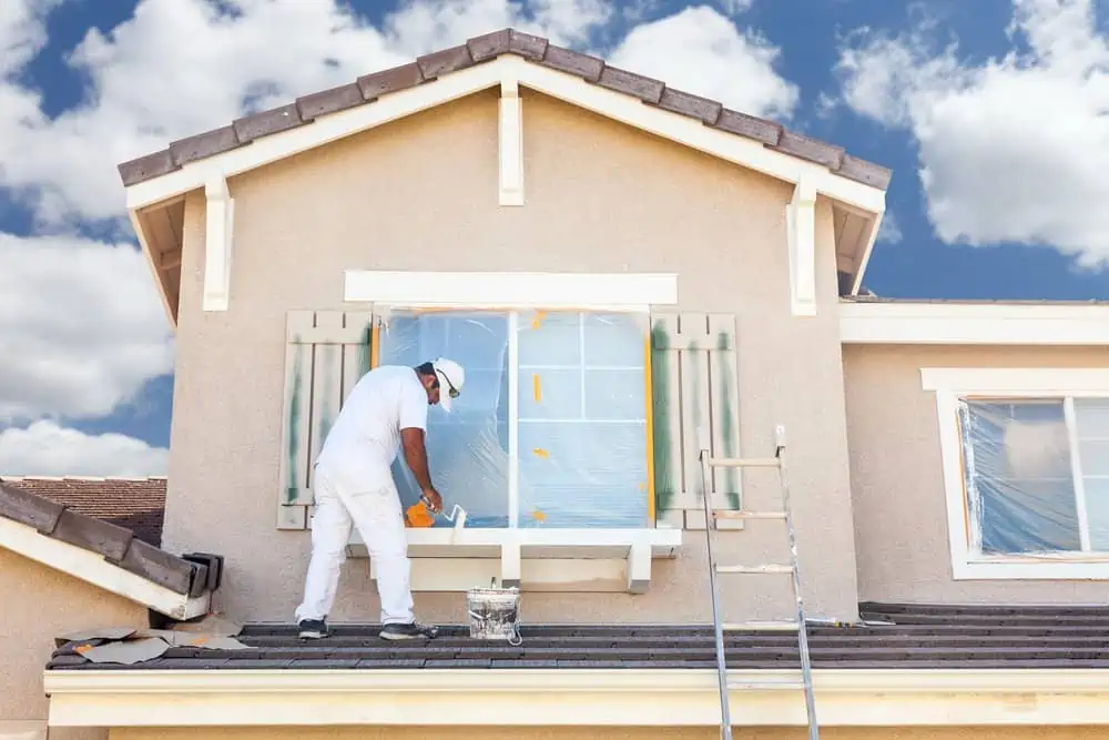 Man painting the window of a two storey house