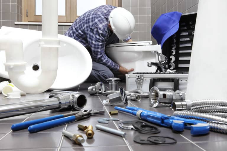 Plumber removing toilet in bathroom